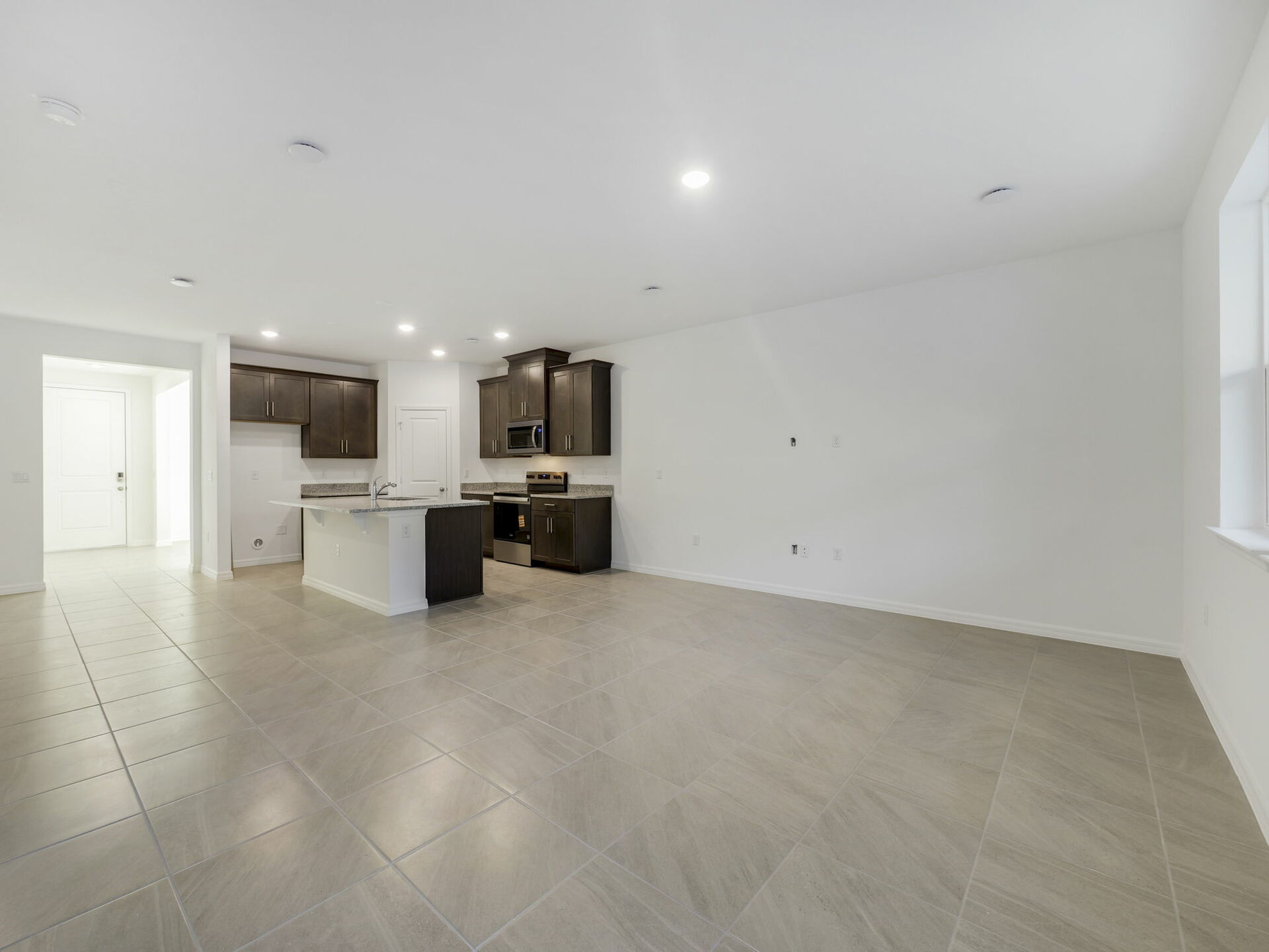 great room overlooking the kitchen with dark brown cabinets and tile flooring