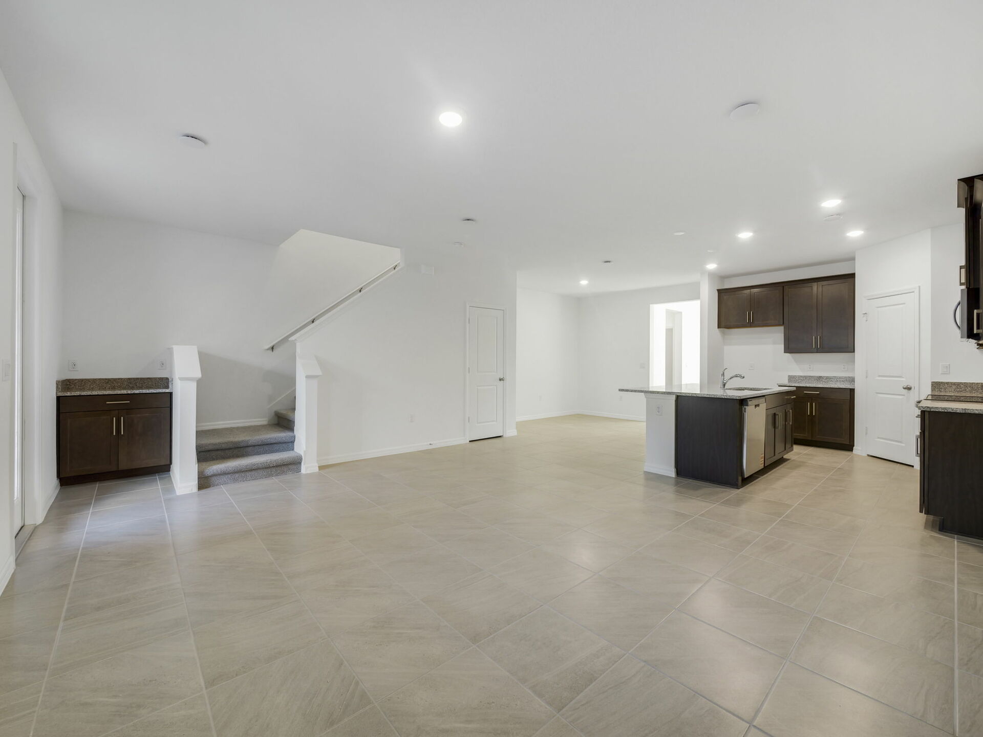 great room overlooking the kitchen with dark brown cabinets and tile flooring