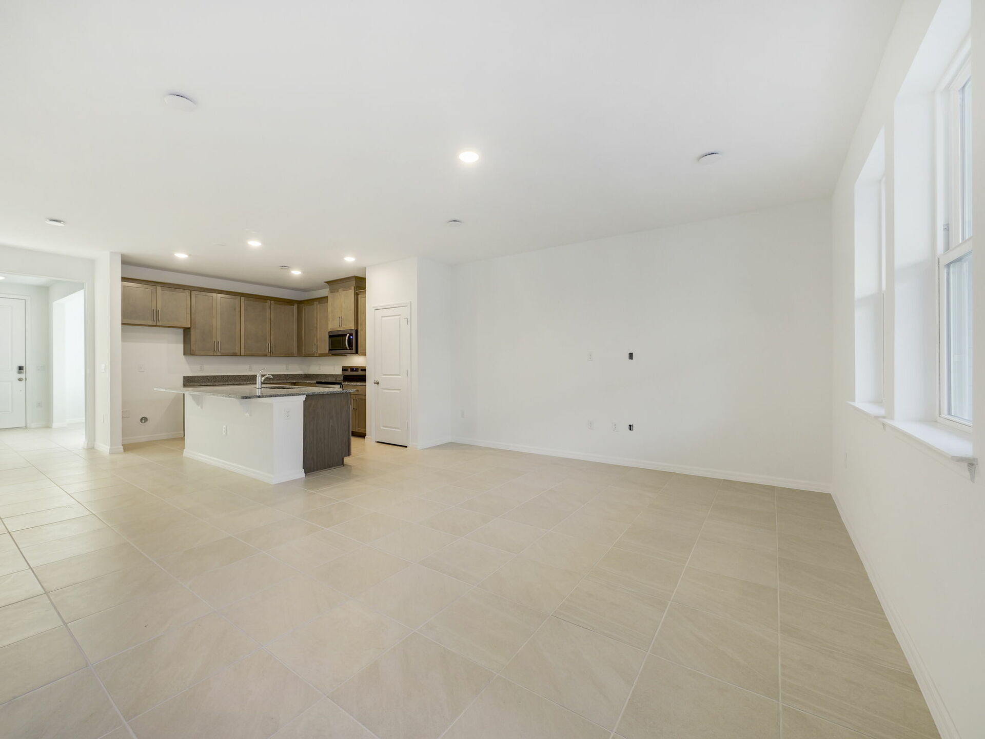 great room overlooking kitchen with brown cabinets and tile flooring