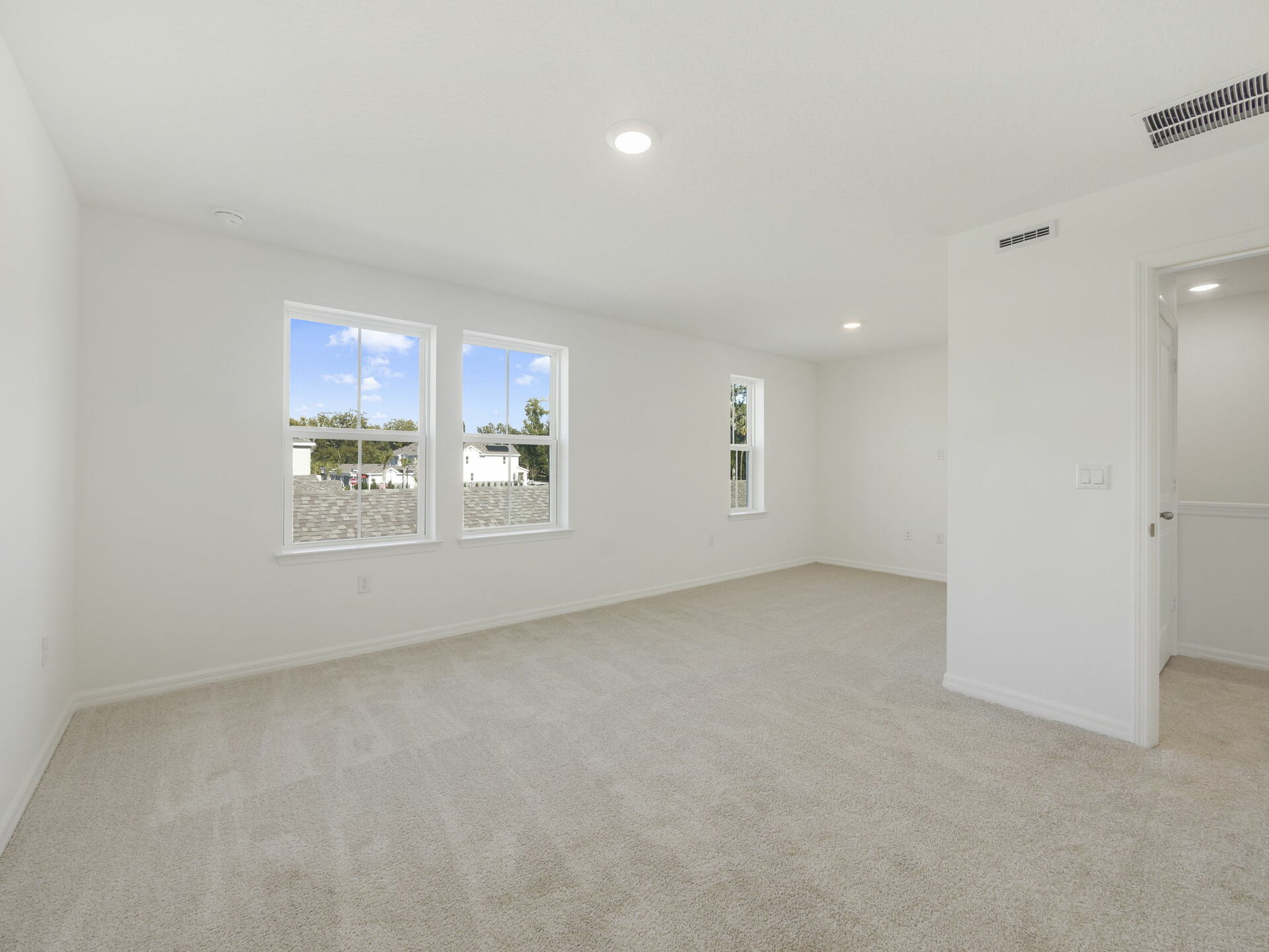 primary bedroom with carpet and three windows