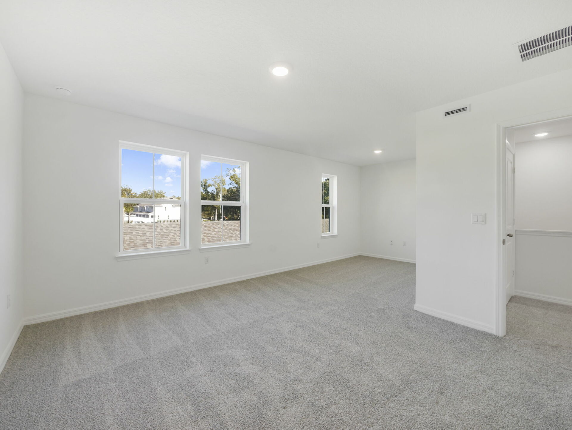 primary bedroom with carpet and three windows
