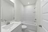 secondary bathroom with white cabinets, white countertops, and a shower and tub combination