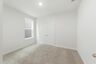 secondary bedroom with carpet flooring, white trim, and large windows