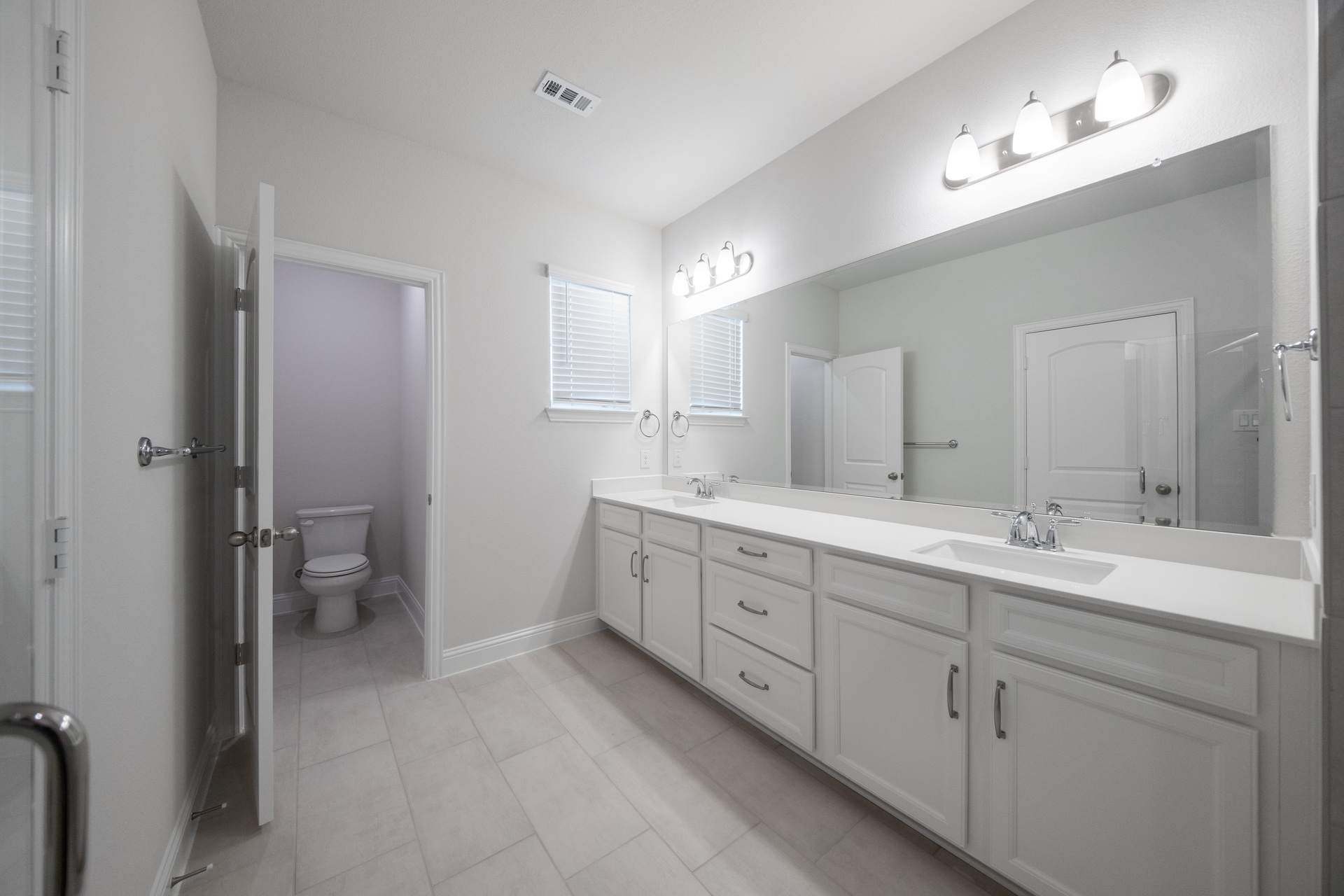 spacious primary bathroom with double sinks and tile flooring