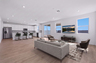 open-concept space with a large grey couch, glass coffee table, and brown rug