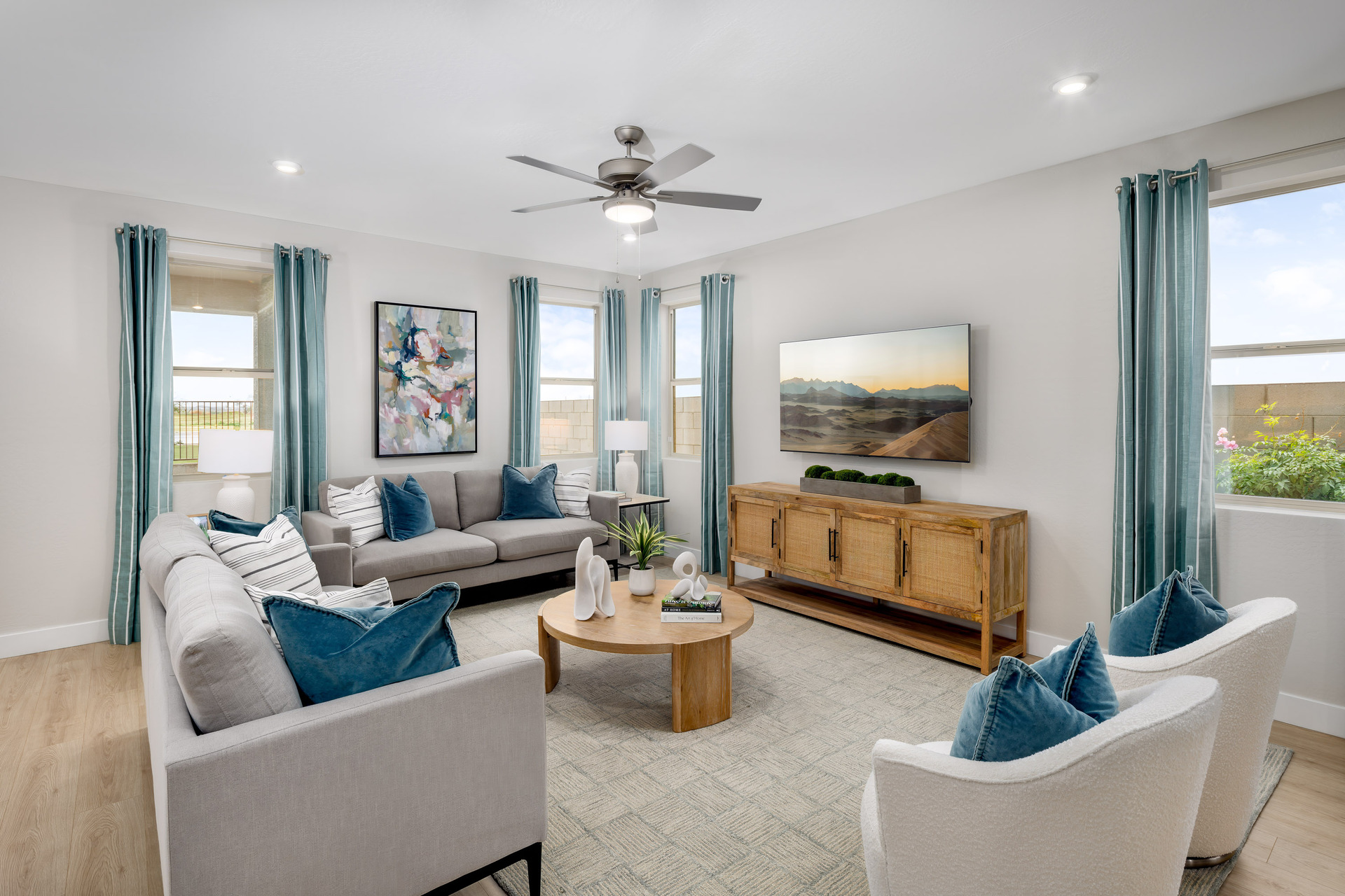 open-concept great room with large couch, wooden tv console, and teal accent colors