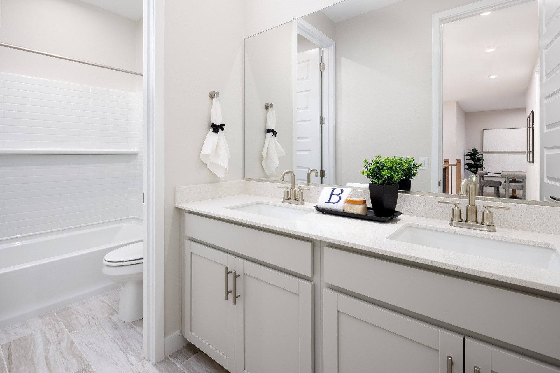 bathroom with light grey cabinets, double sink, and brushed nickel faucets