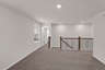 upstairs loft with open hand railing and tan carpets