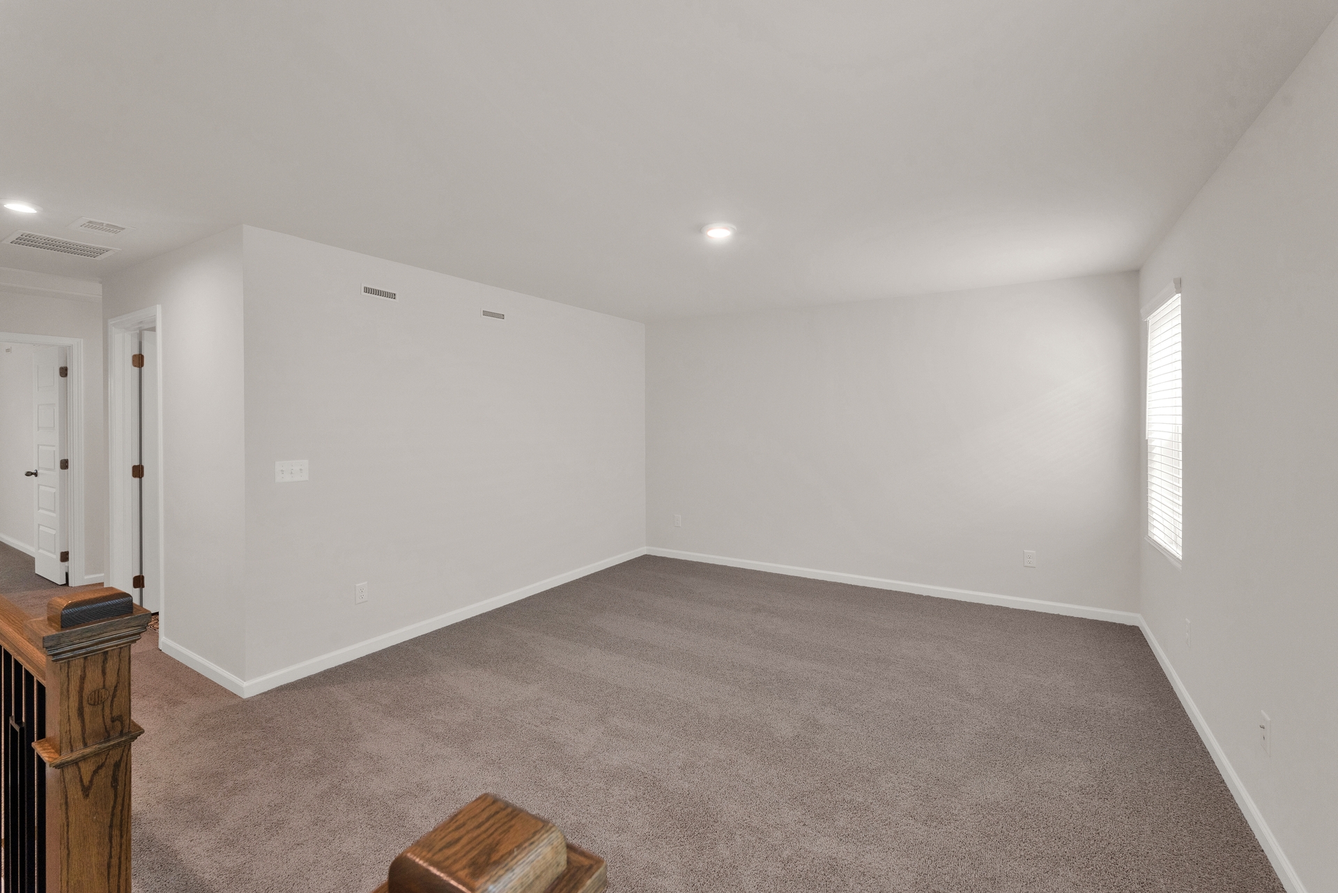 loft with tan carpet and a window letting in natural light