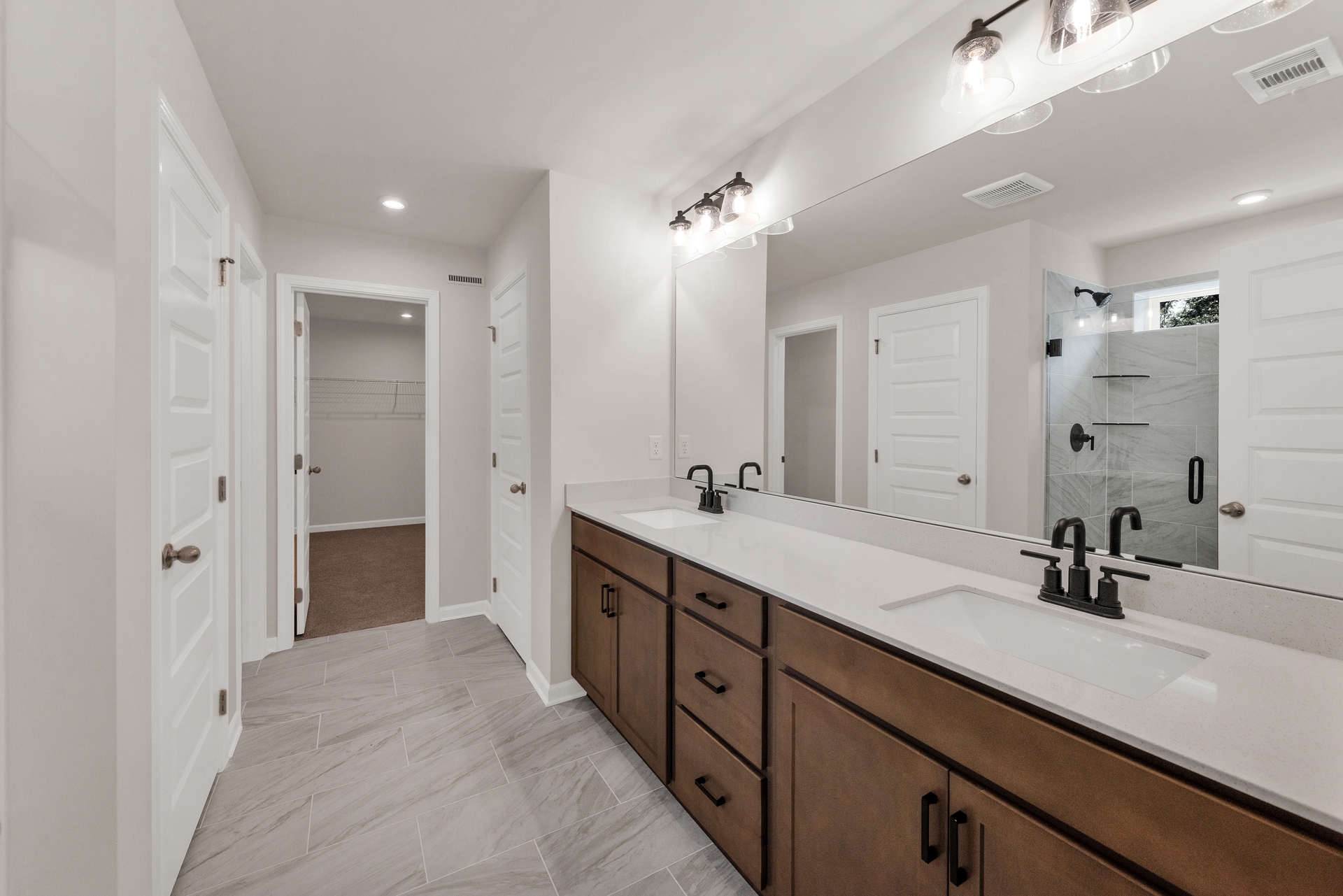 primary bathroom with dual sink vanity and tile floors