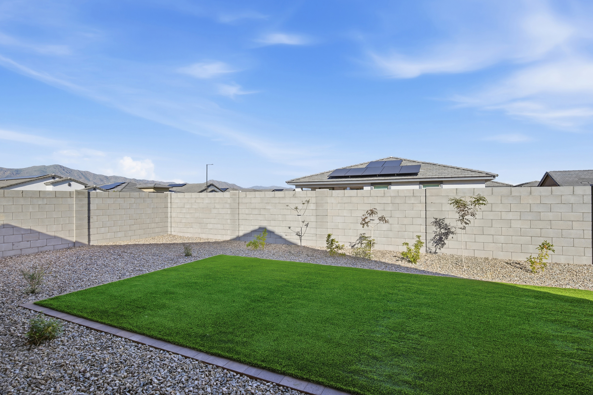 spacious backyard with artificial grass and concrete block wall