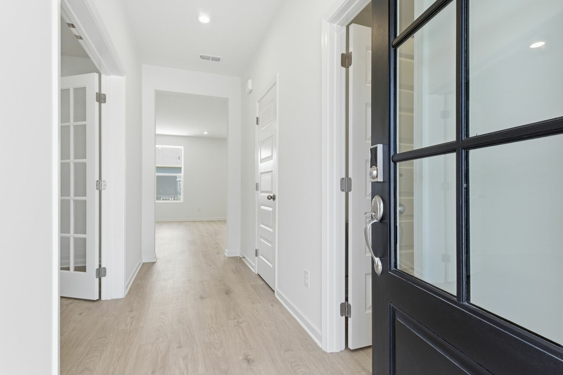foyer with black entry door, white walls, light wood floor and a study with french doors