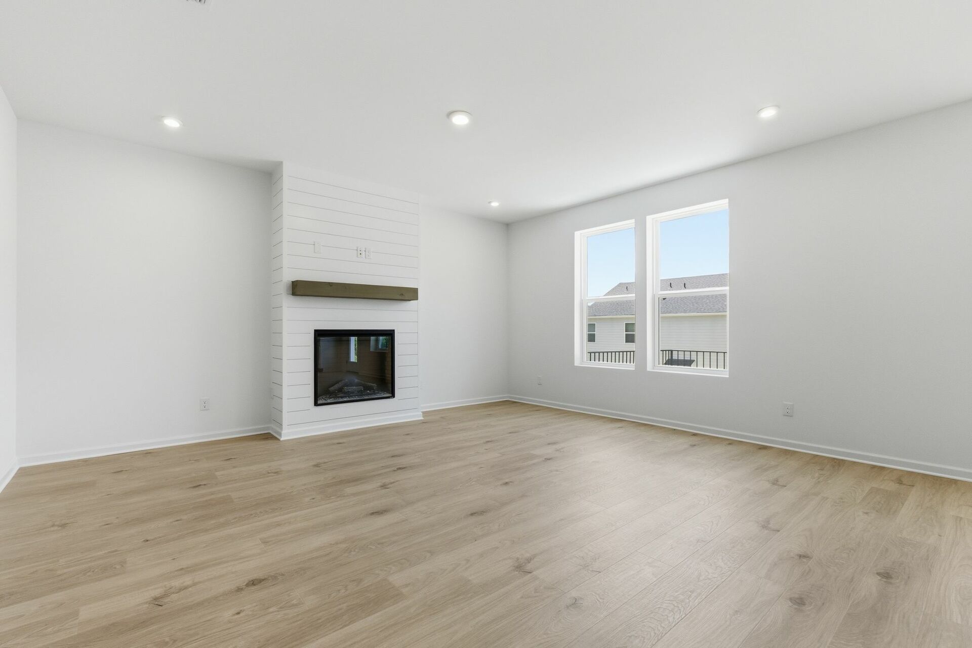 great room with white shiplap fireplace, large windows and wood floors