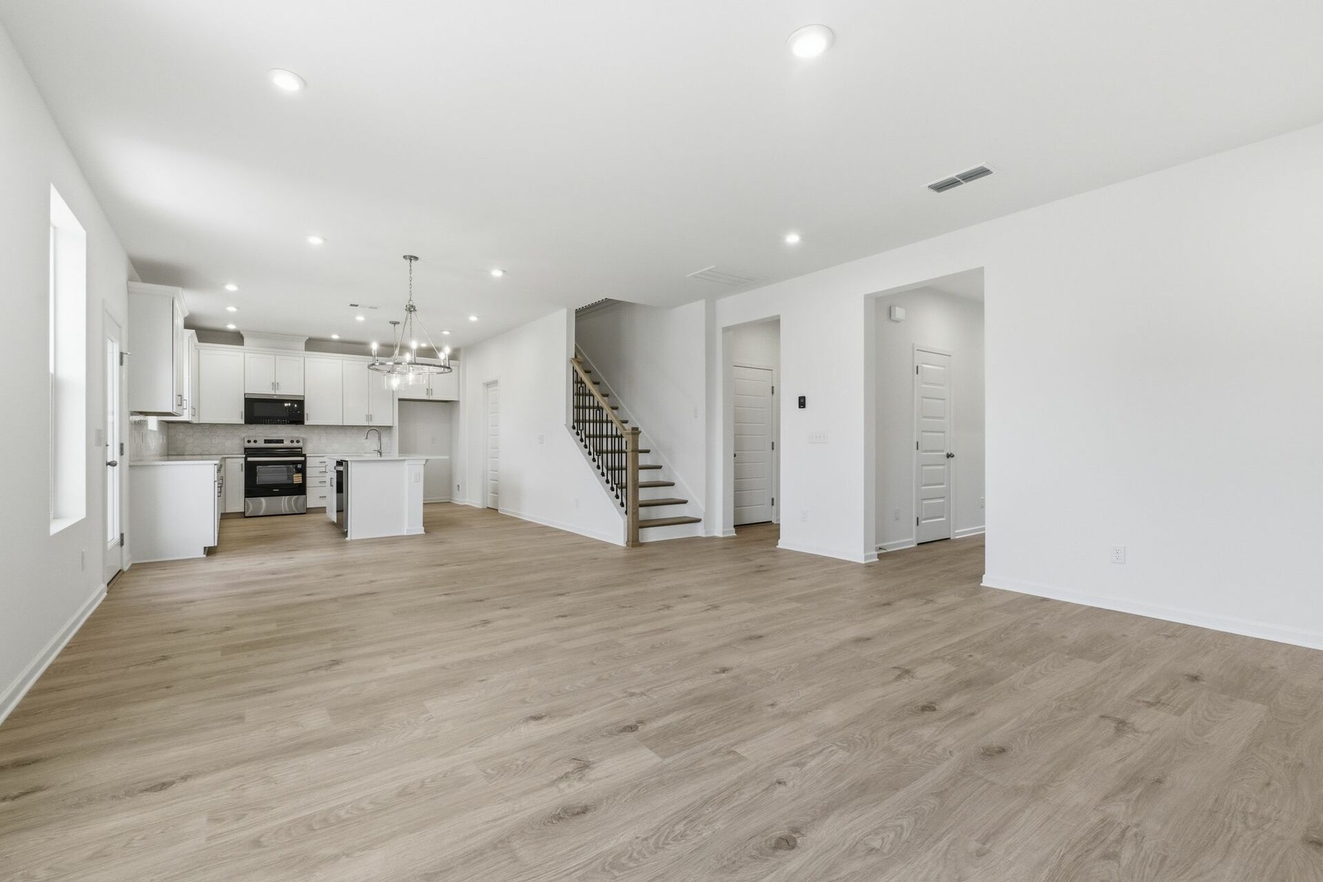 great room with white shiplap fireplace, large windows and wood floors