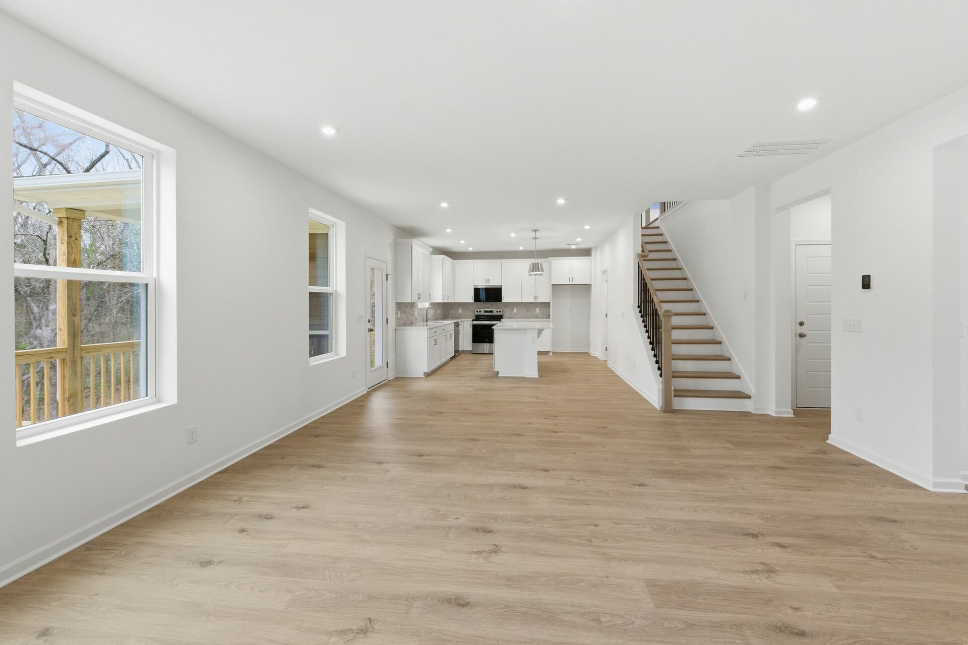 great room with wood flooring, large windows, and open to the kitchen