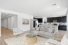 open-concept space with large grey couch, white accent chairs, and white rug