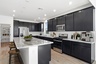 open-concept kitchen with black cabinets, granite countertops, and wooden barstools