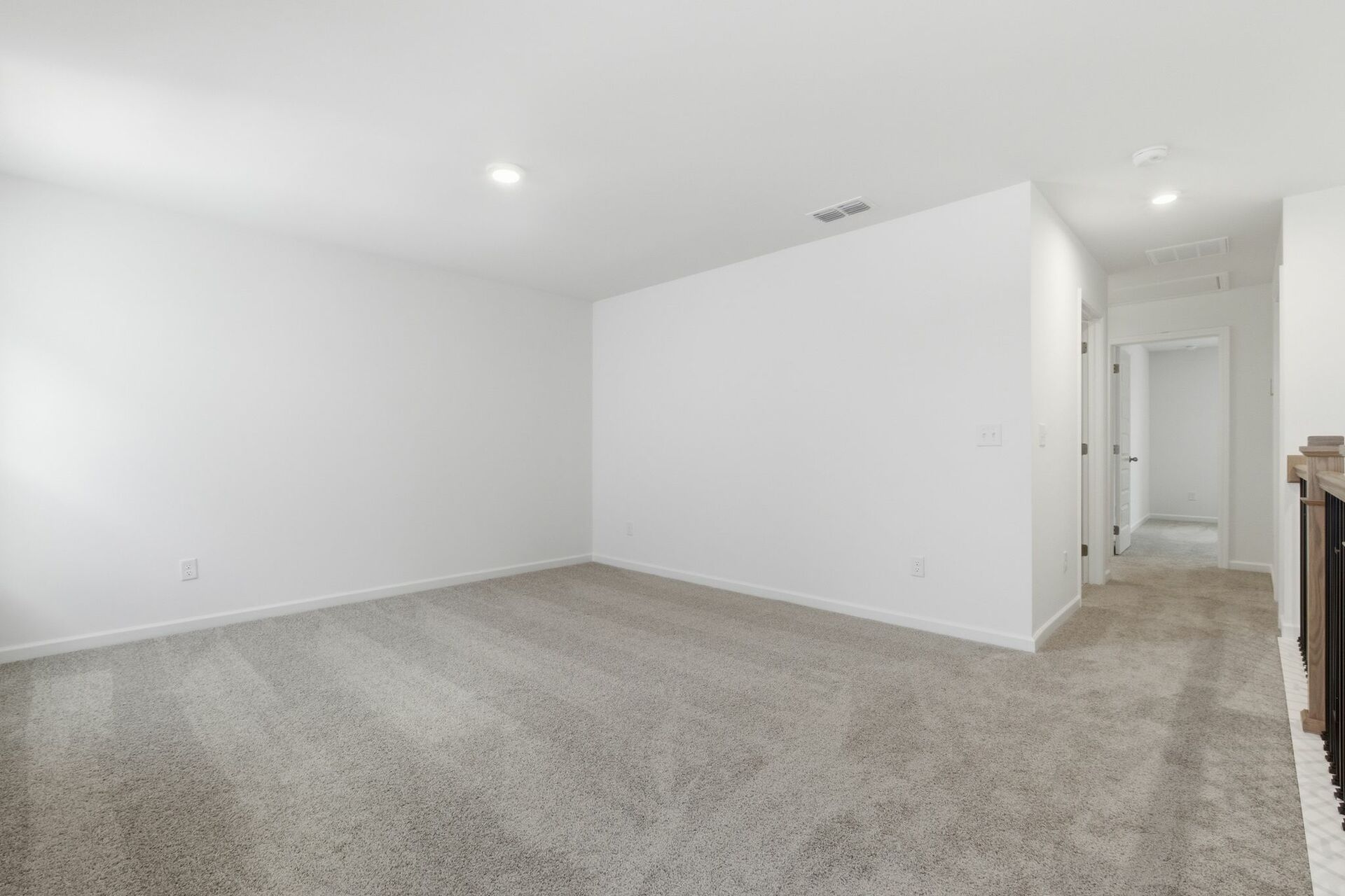 loft with carpet, to windows, and oak tread stairs with iron railing