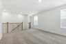 loft with carpet, to windows, and oak tread stairs with iron railing