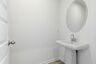 powder room with oval mirror and standing sink
