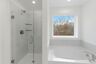primary bathroom with tile flooring, double sink vanity, walk-in shower, and large soaking tub