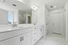 primary bathroom with white cabinets, white sink, large tub and shower