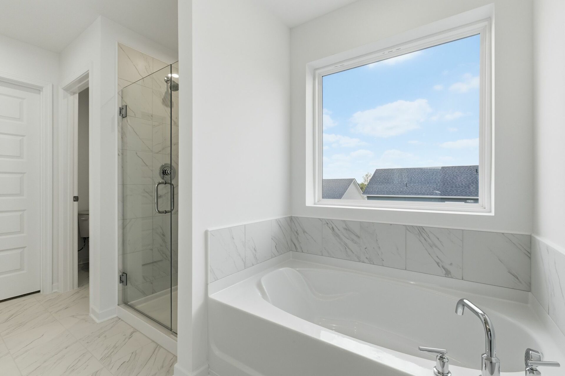primary bathroom with white cabinets, white sink, large tub and shower