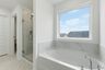 primary bathroom with white cabinets, white sink, large tub and shower