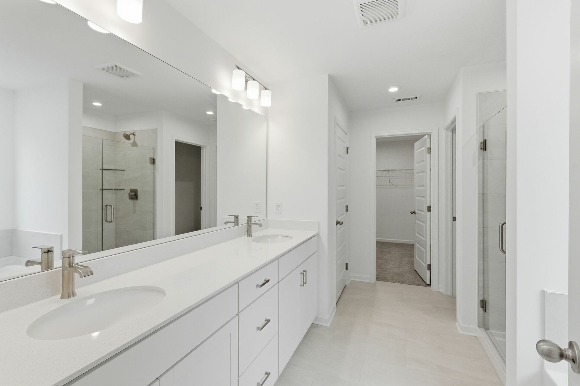 primary bathroom with tile flooring, double sink vanity, walk-in shower, and large soaking tub