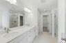 primary bathroom with tile flooring, double sink vanity, walk-in shower, and large soaking tub