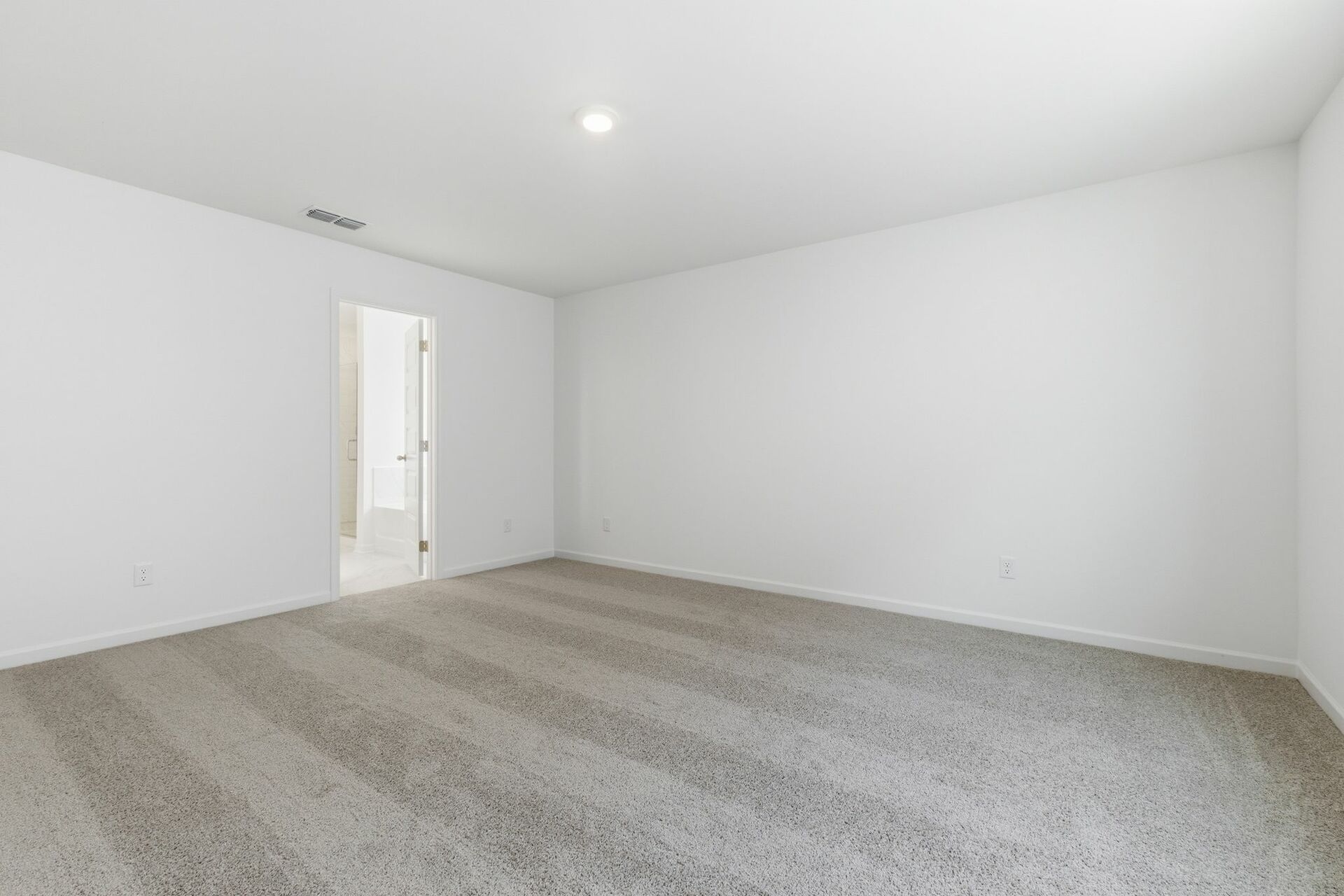 primary bedroom with carpet, large windows, walk in closet and attached bathroom