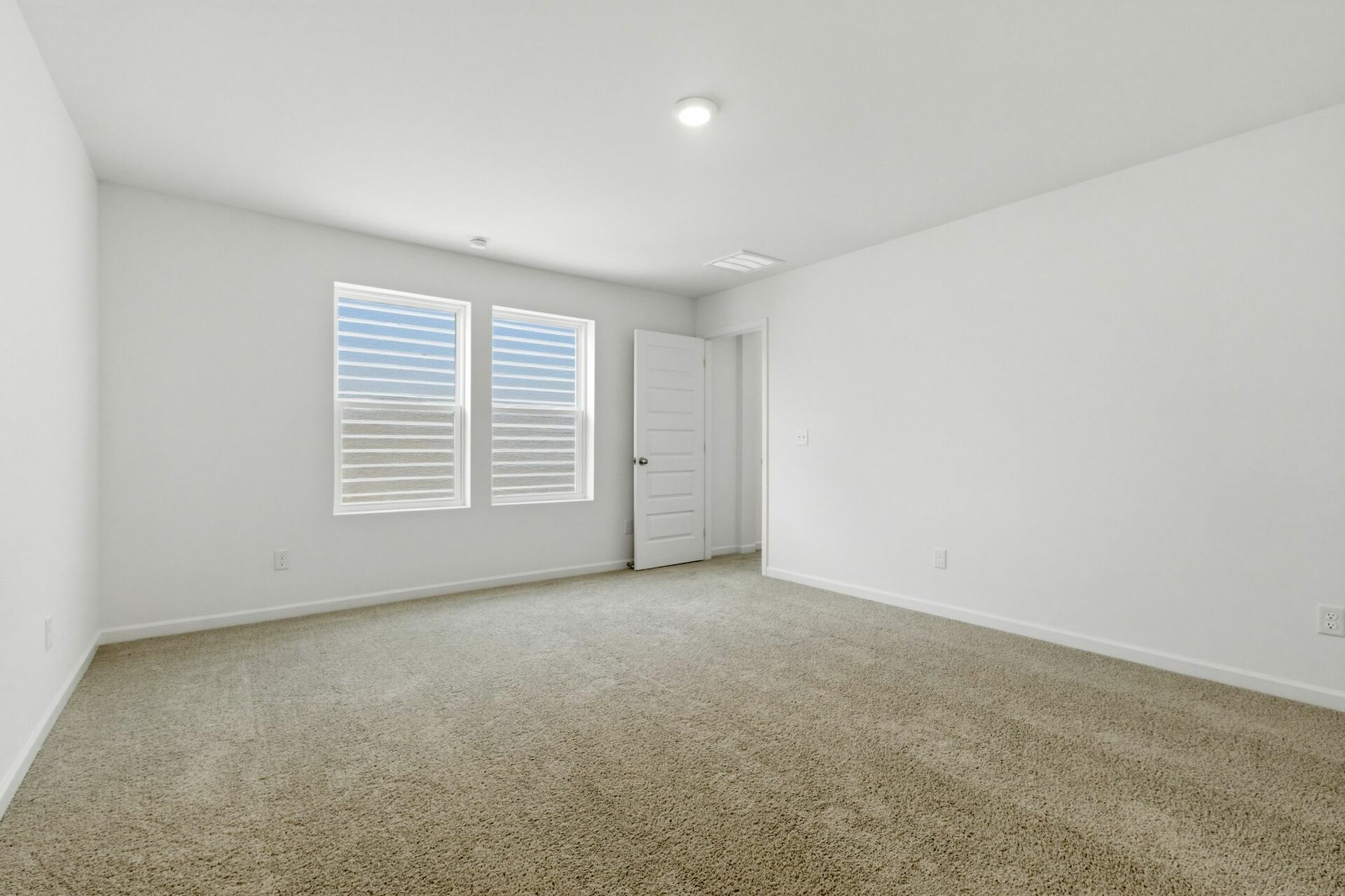 primary bedroom with carpet, large windows, walk in closet and attached bathroom