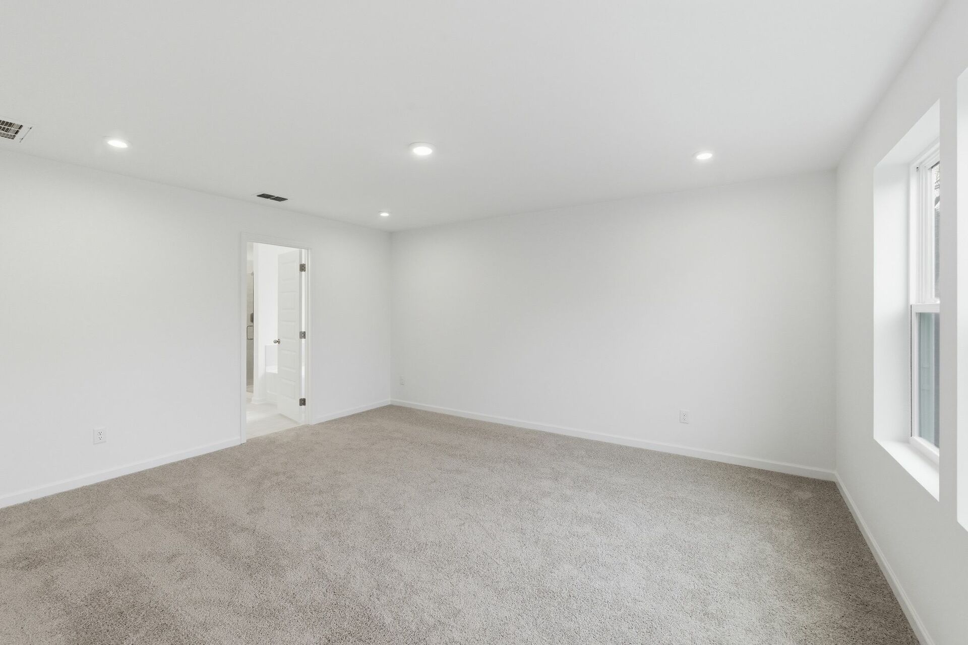 primary bedroom with carpet flooring, white trim, and large windows