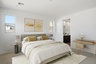 spacious bedroom with a king-sized bed with yellow accent pillows, oak vanity, and grey nightstands