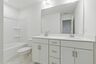 bathroom with tub, dual sink vanity and white cabinets