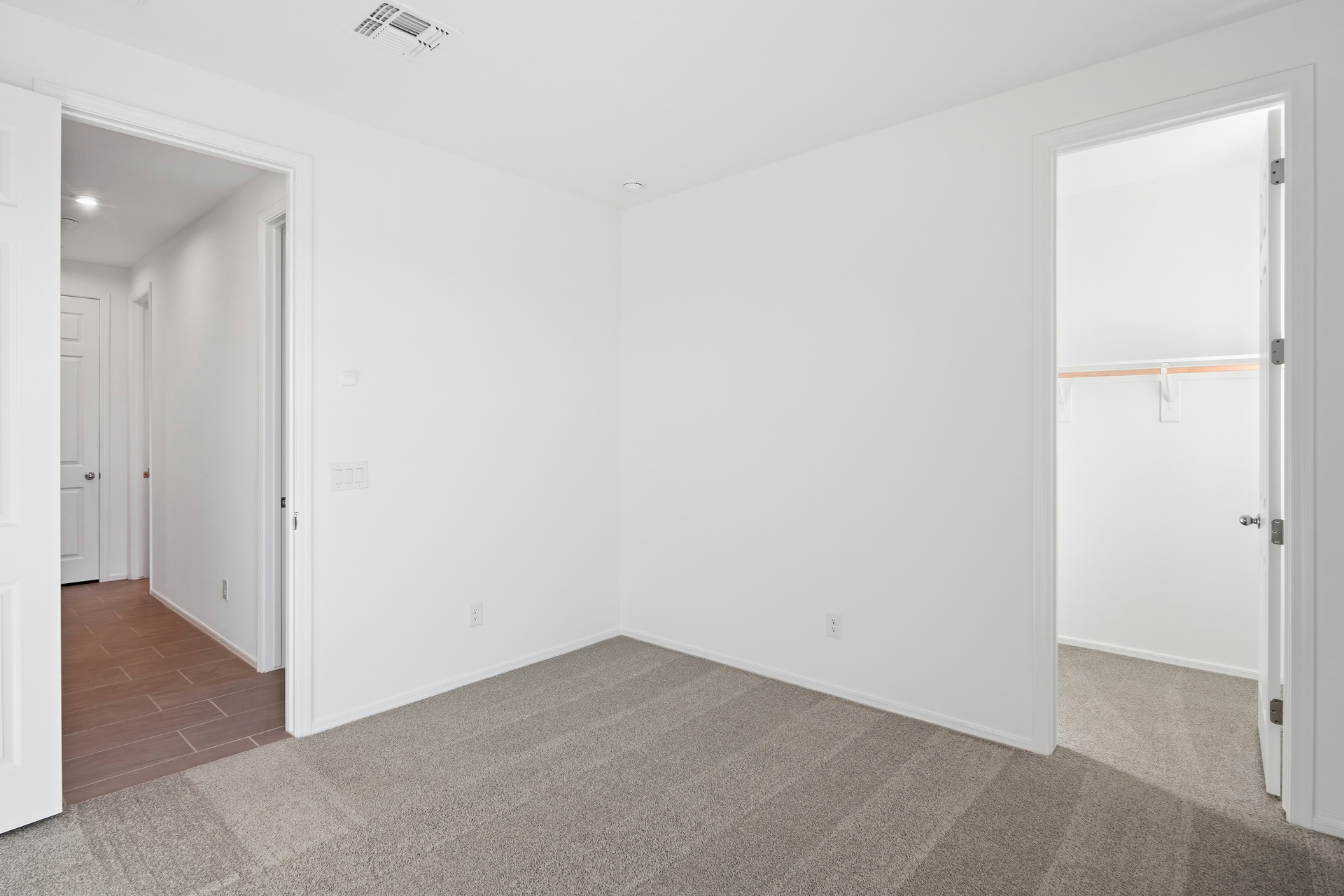 bedroom with light gray carpet and walk-in closet