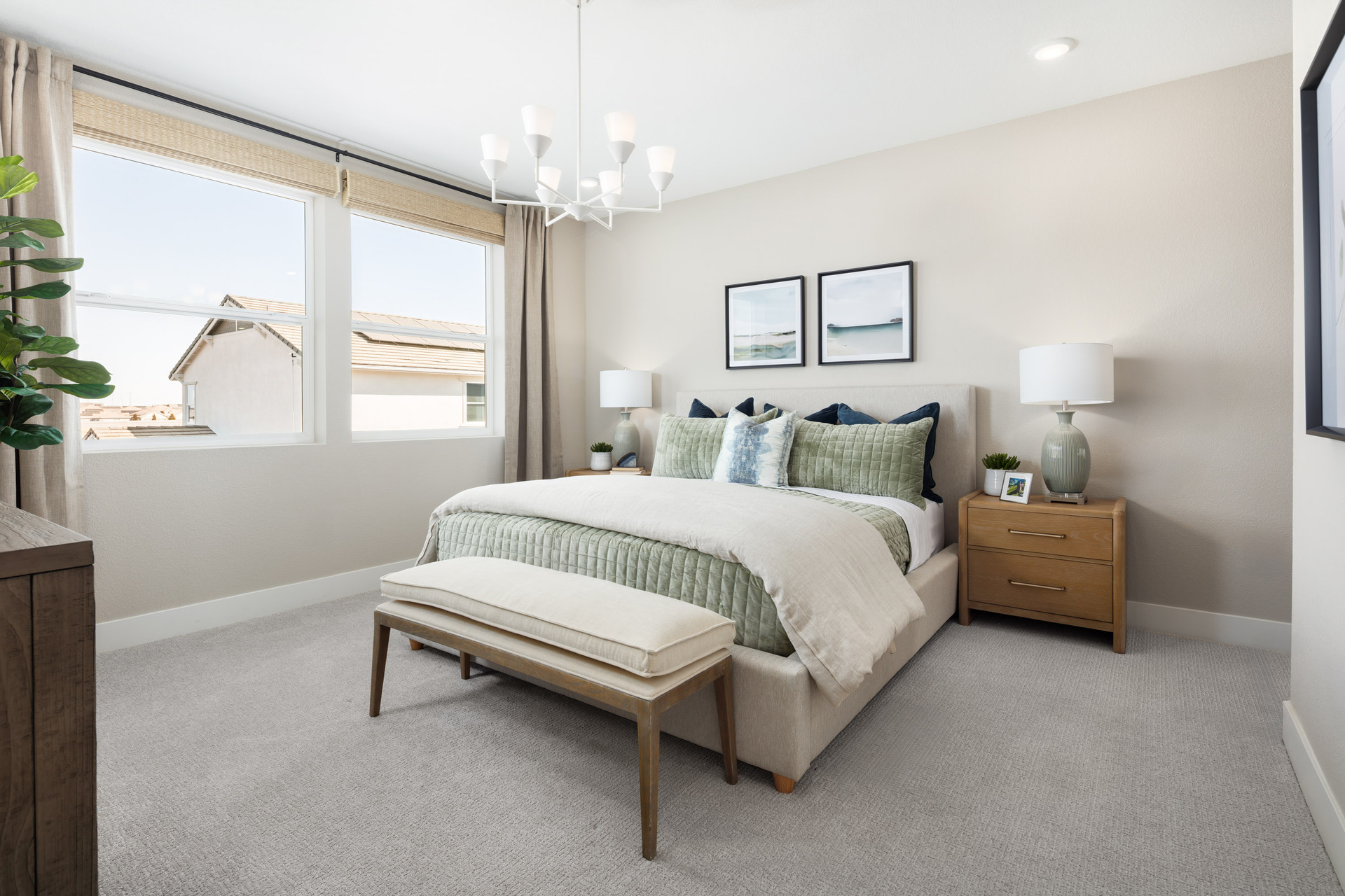 bedroom with tan upholstered bed, light green & blue bedding, wood nightstands, and white hanging ceiling light fixture