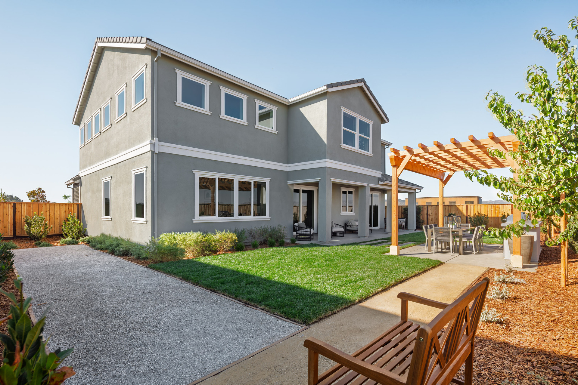 backyard with wood bench, grassy area, covered patio, and wood pergola over outdoor dining table