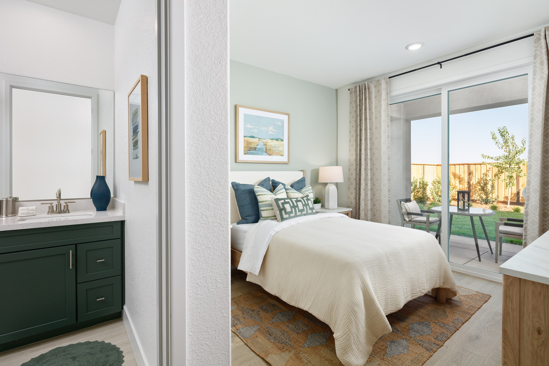 bedroom with light green walls, wood floors, white upholstered bed, and sliding glass door to backyard