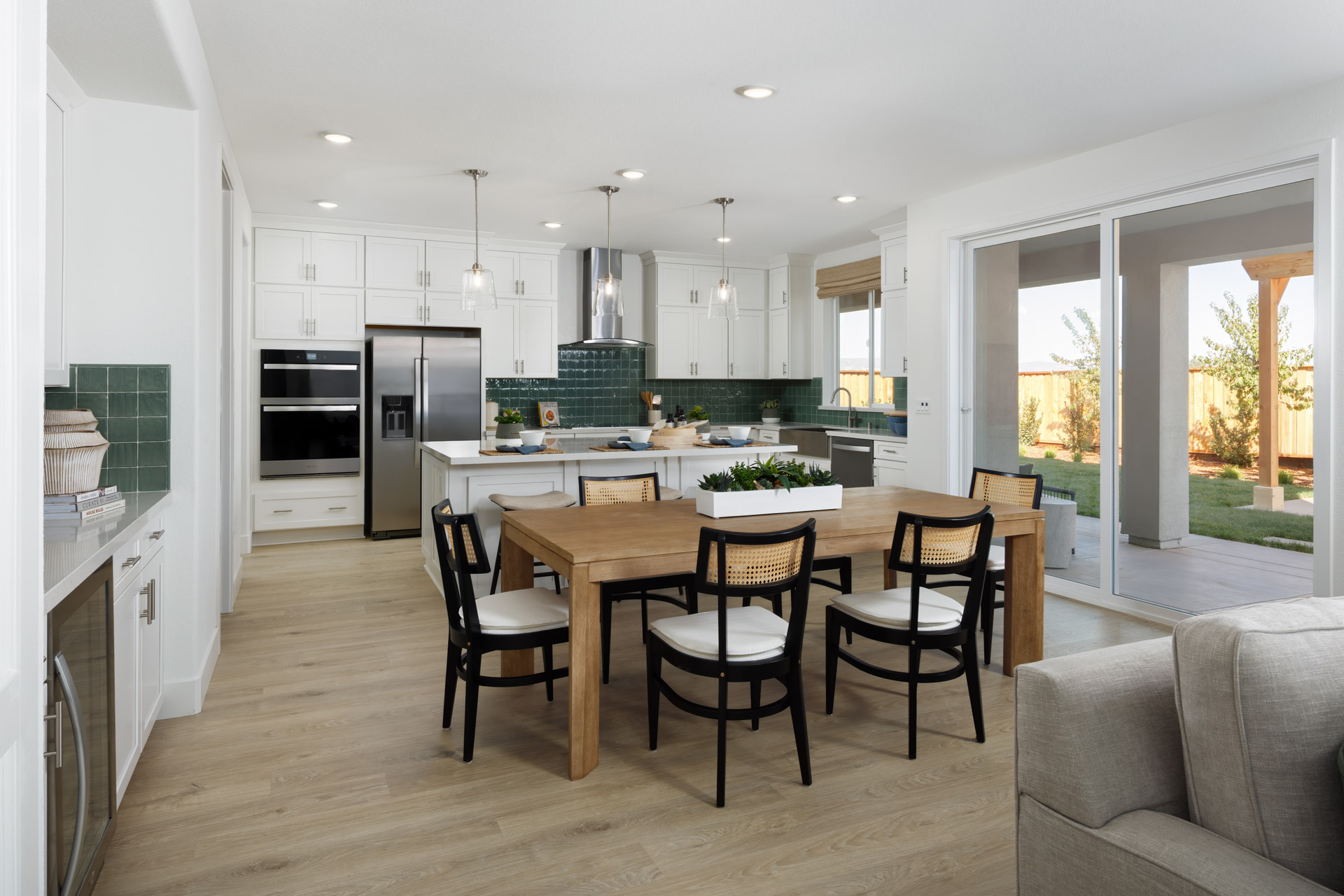 dining room with wood floors, wood table with seating for six, beverage bar, and sliding glass door to back patio
