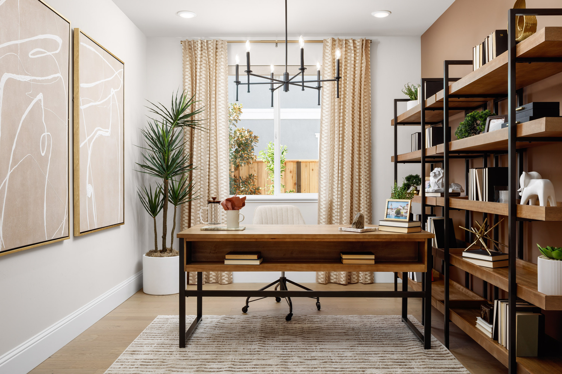 study with full wall wood & iron bookcases, wood desk, hanging black light fixture, window, and potted plant in corner