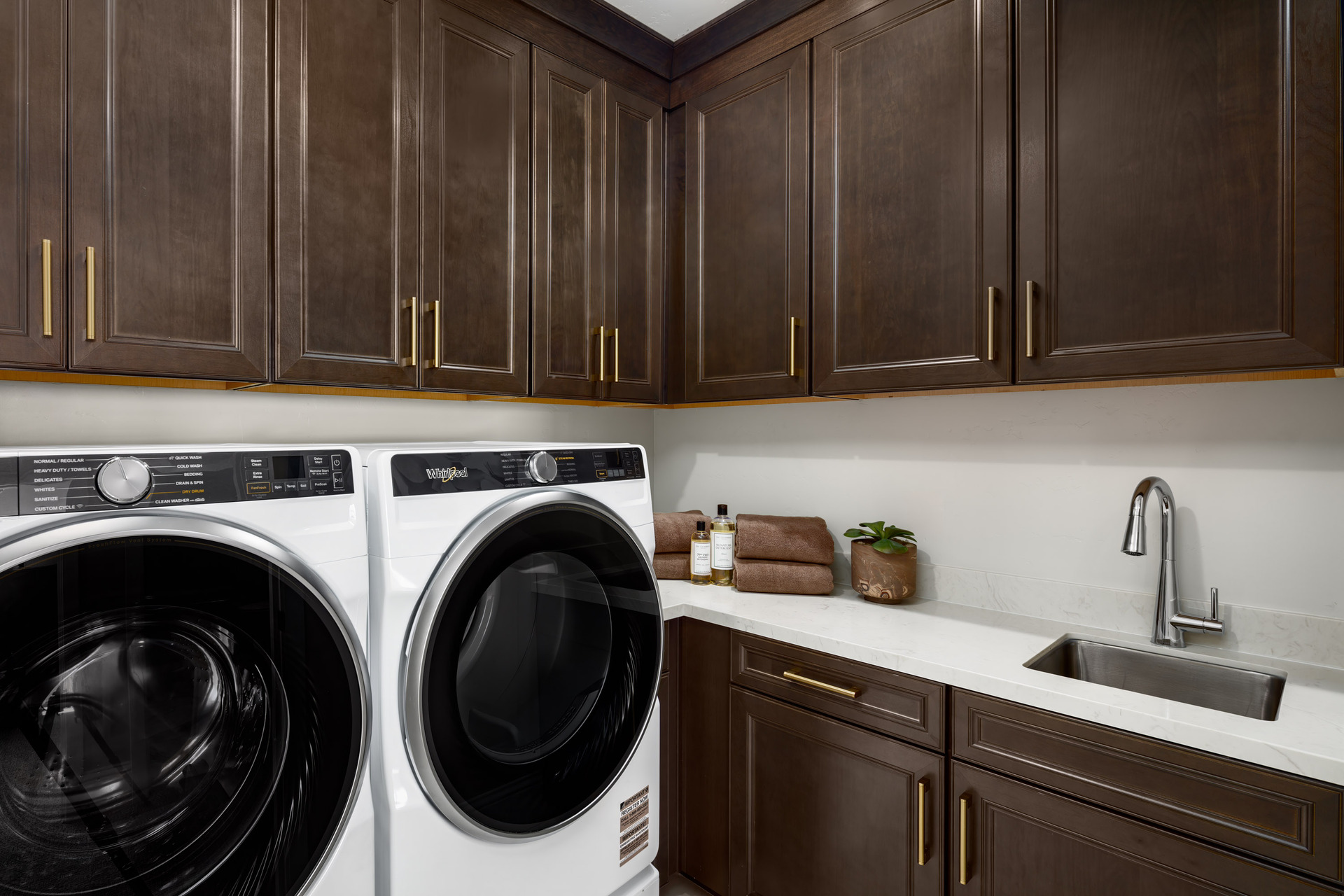 laundry room with espresso upper & lower cabinets, sink, white counters, and white washer & dryer
