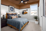 bedroom with rust-colored painted ceiling & sports theme, window, denim blue bedding, wood bed, and potted plant in corner 