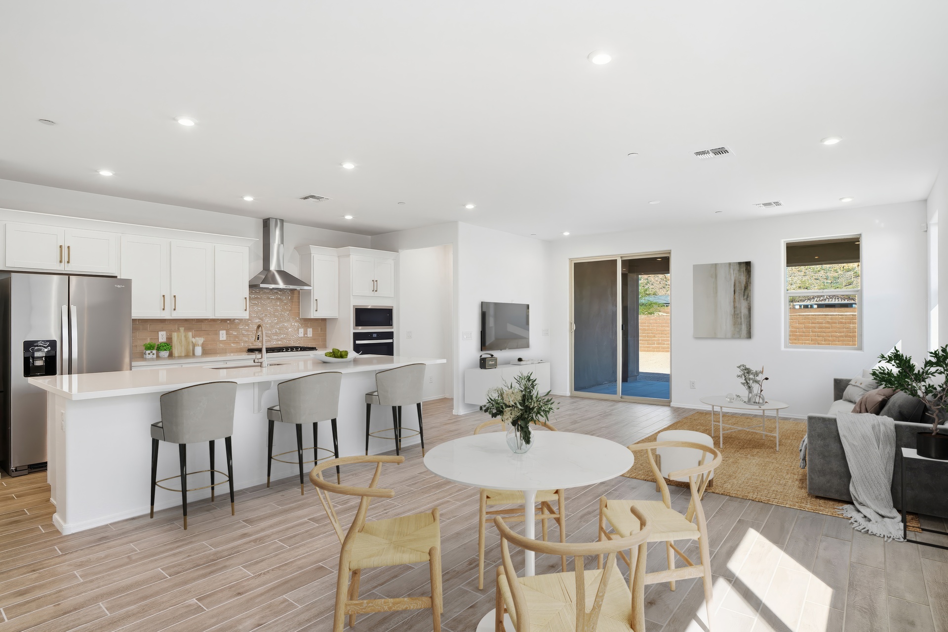 open-concept great room with a white dining table, wooden dining chairs, and quick access to the kitchen