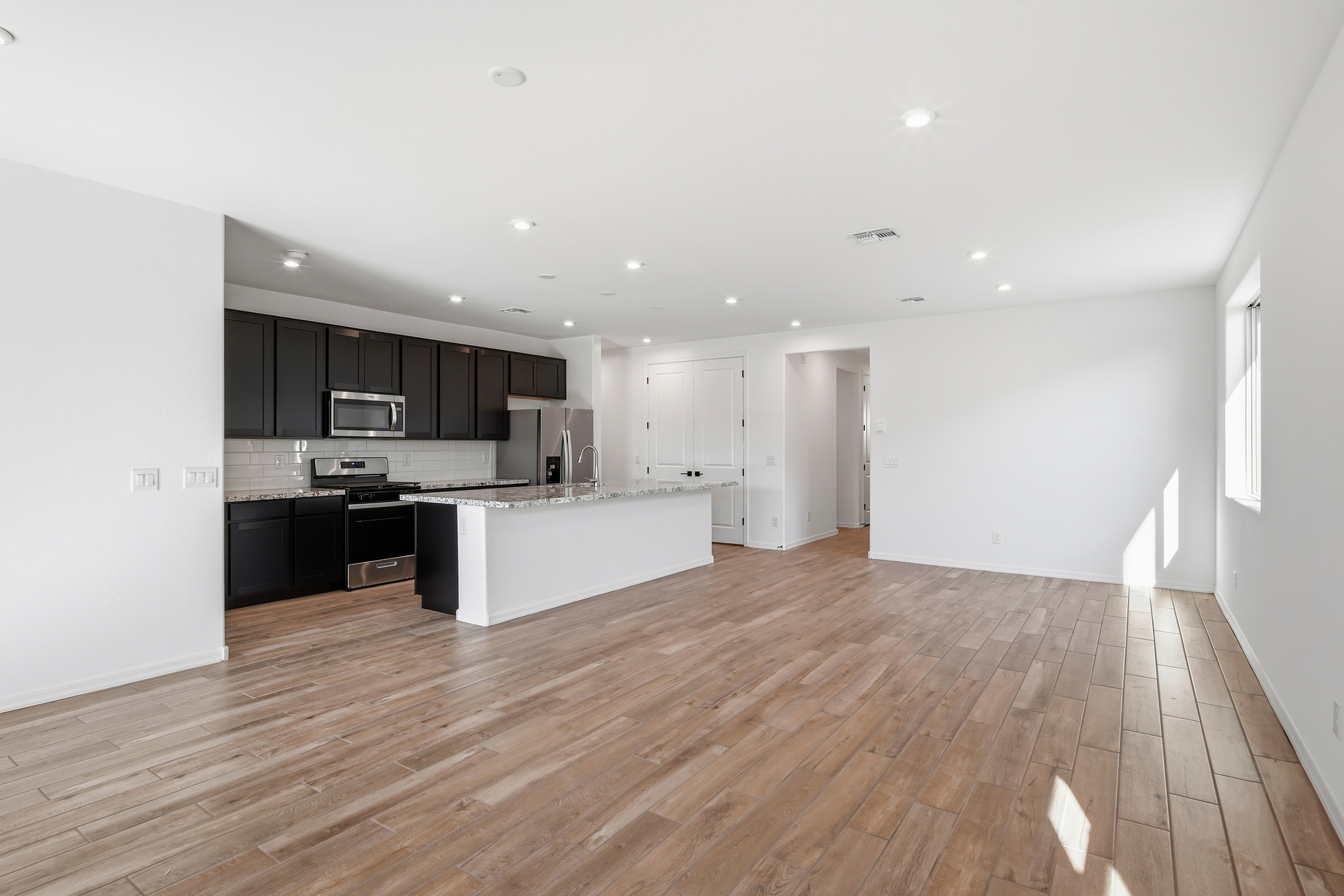 open-concept space with wood-like flooring and recessed lights