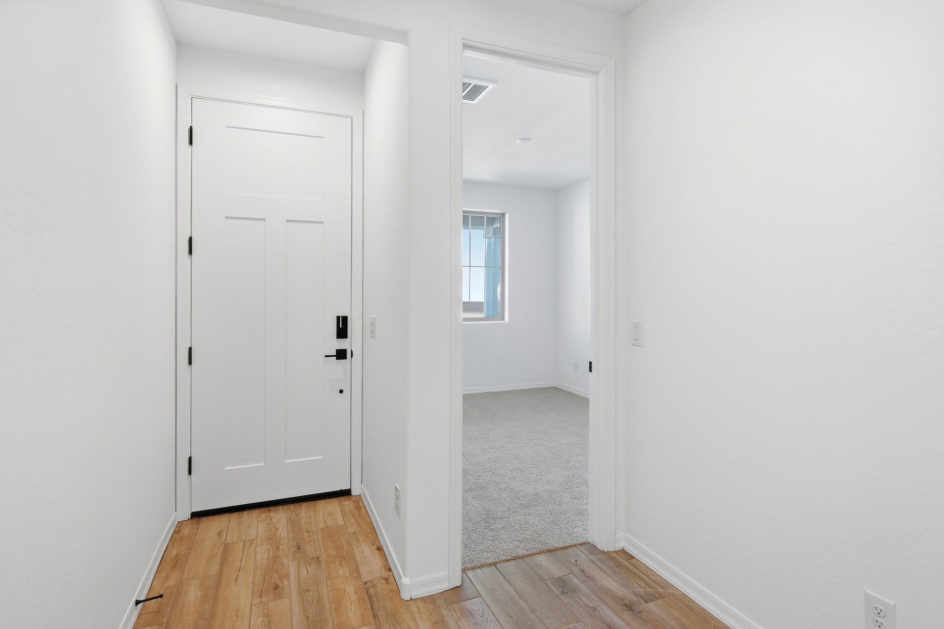 open-concept foyer with wood-like flooring and quick access to the secondary bedroom