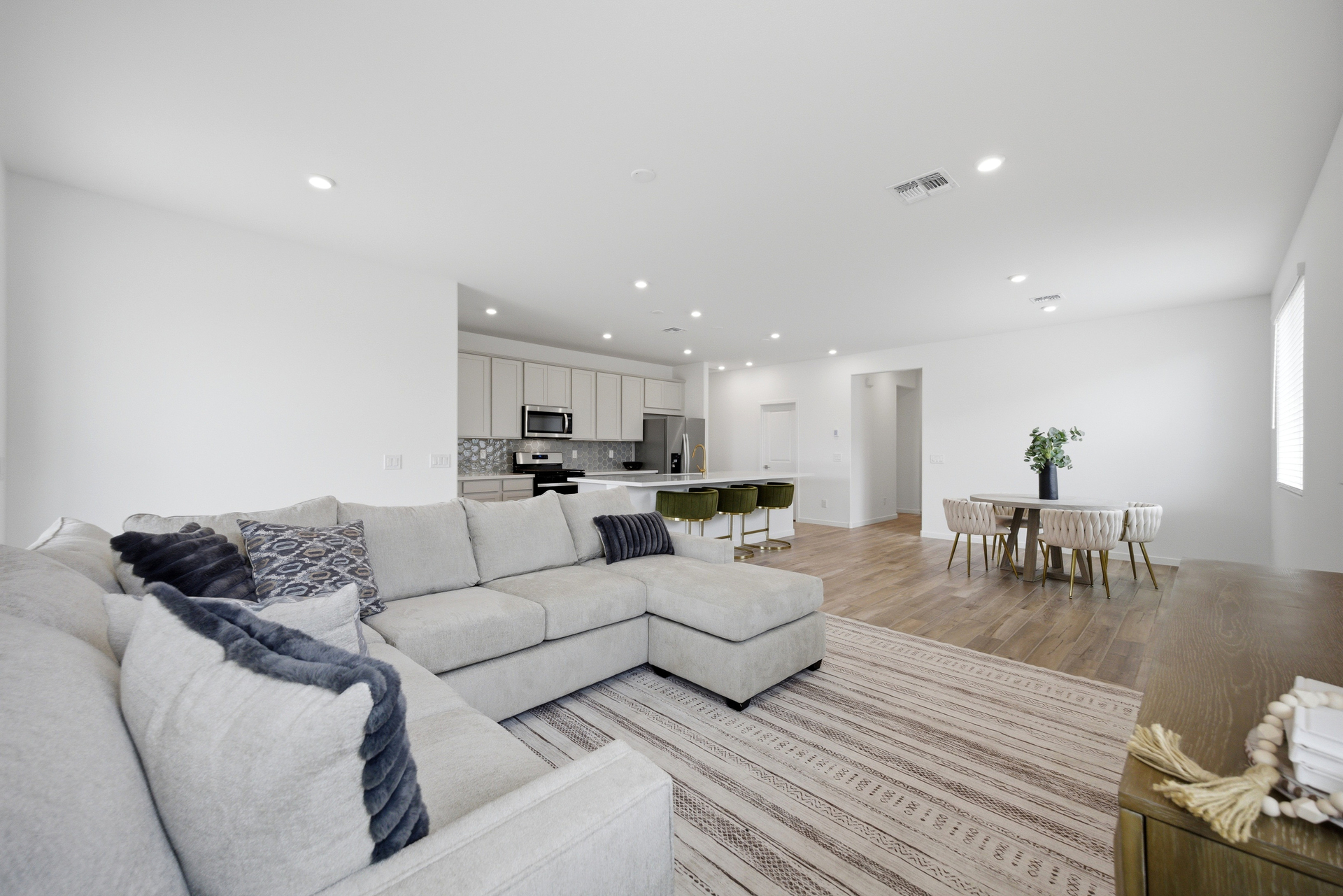 open-concept space with a large grey sectional, white rug, and wooden tv console table