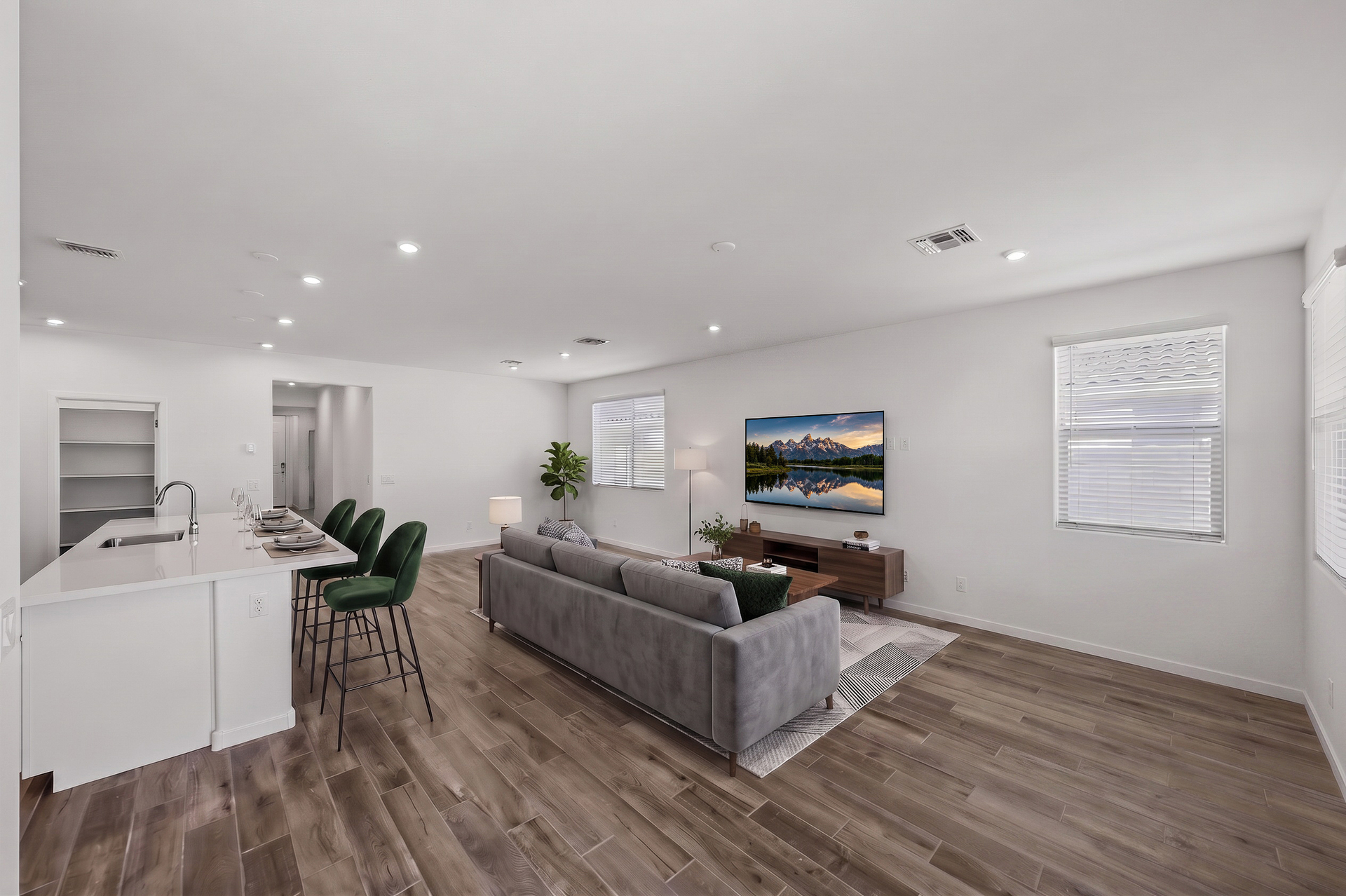 open-concept great room with large grey couch, a white rug, and a walnut coffee table
