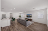 open-concept great room with large grey couch, a white rug, and a walnut coffee table