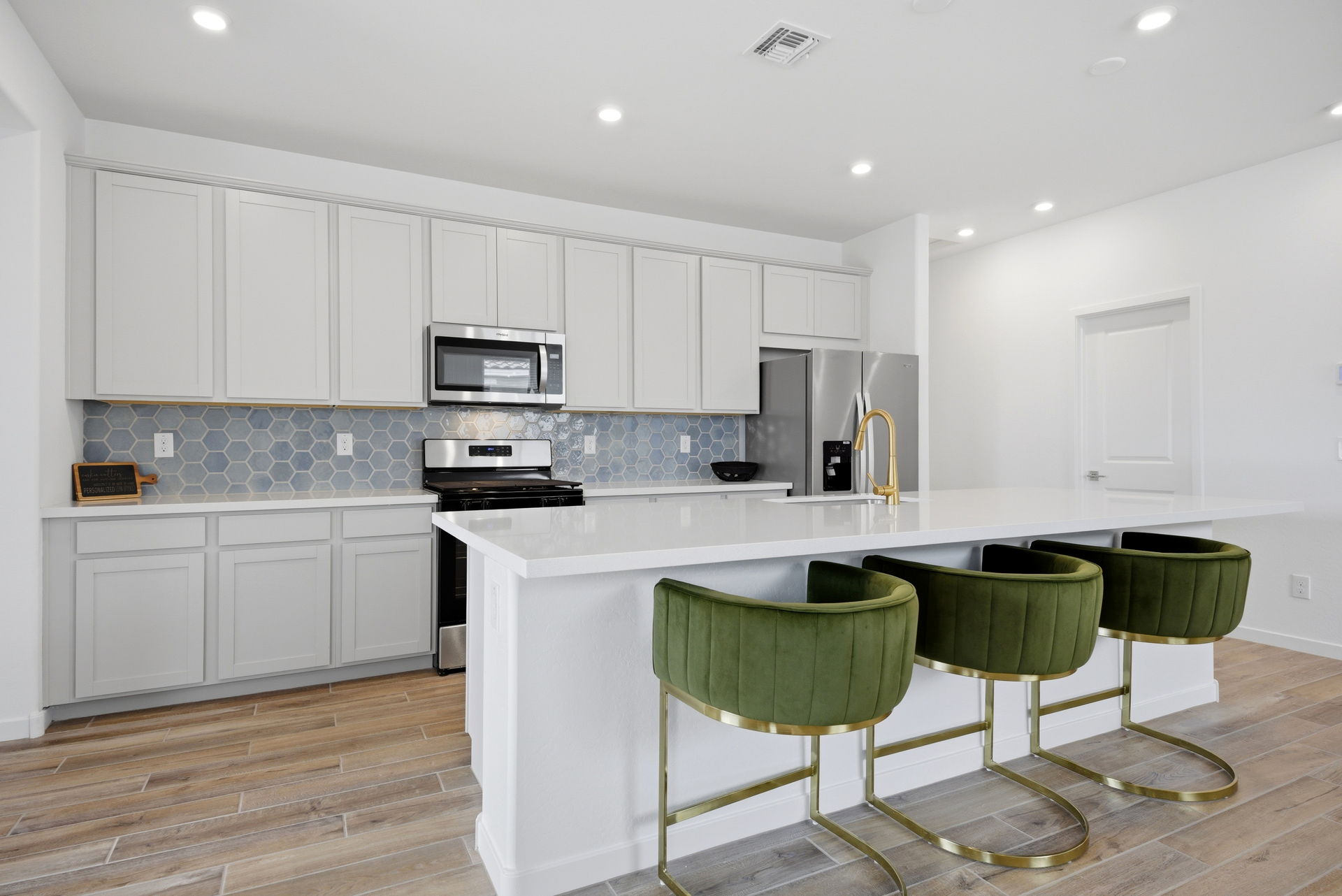 spacious kitchen with quartz countertops, white cabinets, and green barstools